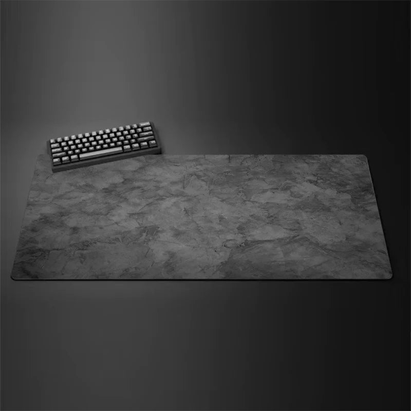 Extended desk mat and mouse pad with stone texture in dark grey shown with keyboard